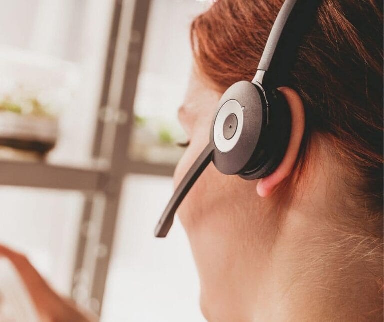 Punatukkaisella naisella on headset päässä, takana on taimien mikroviljelmiä.