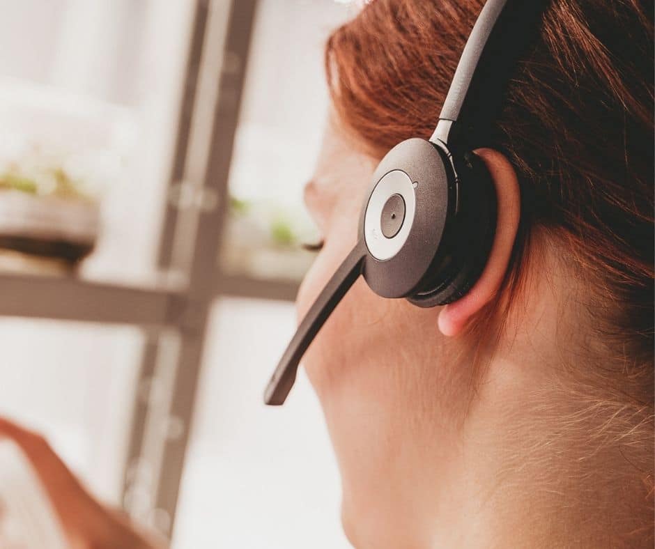 Punatukkaisella naisella on headset päässä, takana on taimien mikroviljelmiä.