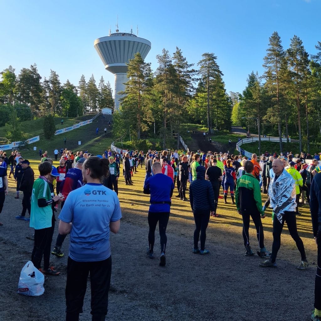Lähtöalue aamuauringossa, ihmiset odottavat ja lämmittelevät omaan juoksuvuoroonsa.